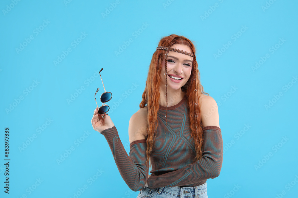 Stylish young hippie woman with sunglasses on light blue background Stylish young hippie woman with sunglasses on light blue background