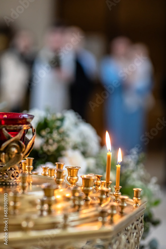 Lit candles in a church with people in the background. Religious and spiritual concept. Design for posters, banners, print.