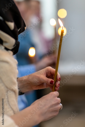 Burning candles in the hands of a woman in the Orthodox church