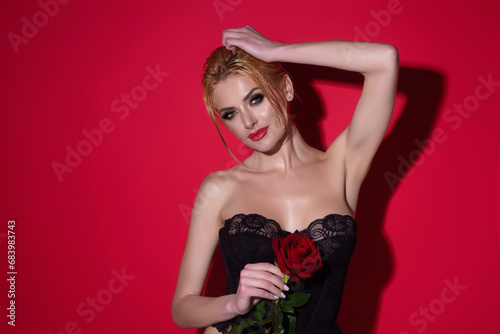 Sexy woman with red rose. Beauty studio portrait. Beautiful model with red rose flower, isolated on red studio background. Charming young girl with perfect makeup.