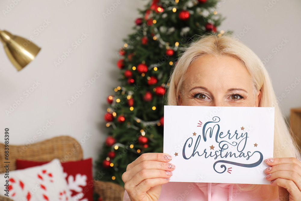 Mature woman with greeting card for Christmas celebration at home, closeup
