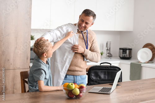Mature doctor with his little son going to work in kitchen photo