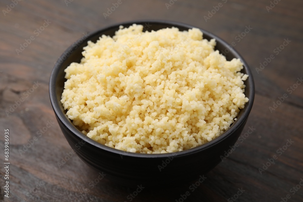 Tasty couscous in bowl on wooden table, closeup Tasty couscous in bowl on wooden table, closeup