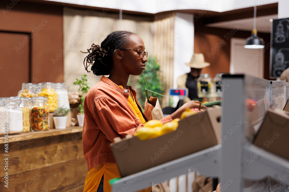 African American female customer in a grocery store. She browses organic vegetables, grains, and sustainable products. The store offers locally grown, zero-waste items. Foreground focus. African American female customer in a grocery store. She browses organic vegetables, grains, and sustainable products. The store offers locally grown, zero-waste items. Foreground focus.
