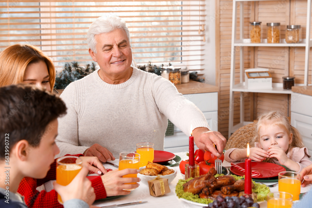 Happy mature man having Christmas dinner with his family in kitchen Happy mature man having Christmas dinner with his family in kitchen