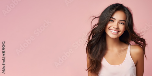 Smimilg young woman with tanned skin and long groomed hair isolated on flat pink pastel background with copy space. Model for banner of cosmetic products, beauty salon and dentistry