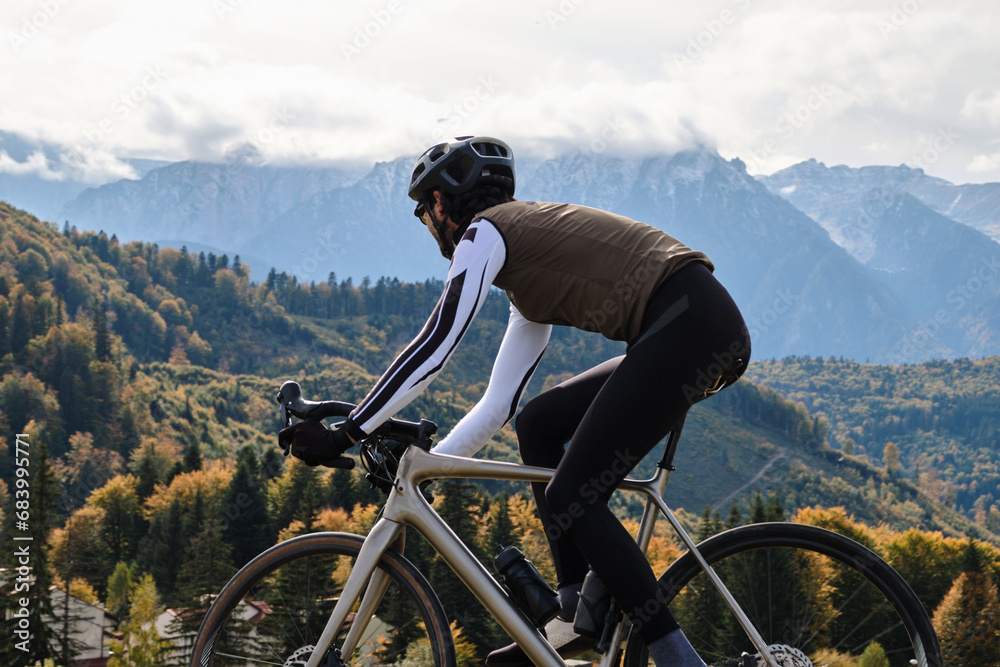 Male cyclist riding gravel bike on gravel road in autumn mountains. Cyclist practicing on gravel road. Gravel biking during the autumn. Sport motivation. Adventure travel on bike. Mountain background.