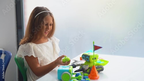 Caucasian student girl hobby playing with toy car remote control panel joystick in white kindergarten . School kid learning radio-controlled car. Child explore electronic toy car in STEM educational