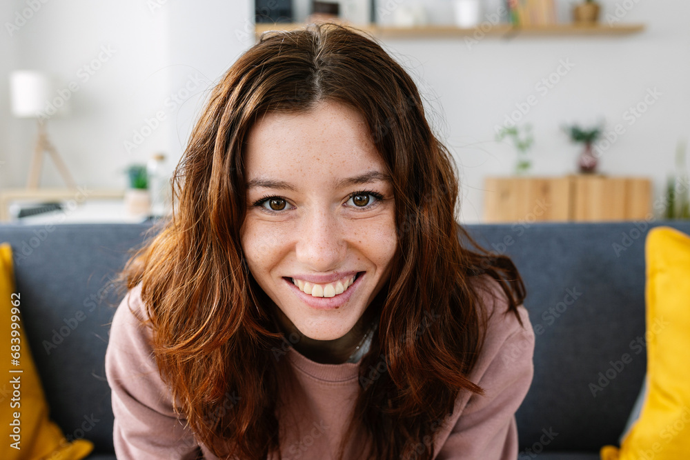 Portrait of young redhead beautiful girl smiling at camera sitting on sofa at home. Happy people concept. Portrait of young redhead beautiful girl smiling at camera sitting on sofa at home. Happy people concept.