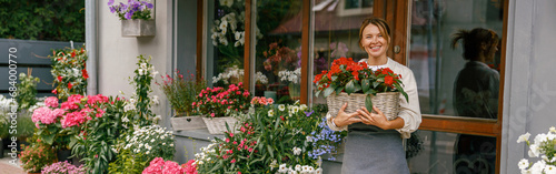 Woman florist small business owner standing in floral store and waiting for client with houseplants