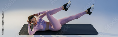 Woman working out her abdominal muscles on studio background. Healthy lifestyle and sport concept