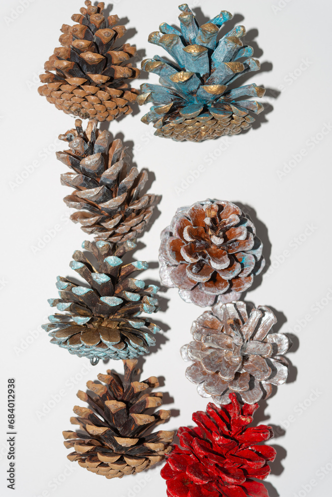 Fototapeta premium holiday evergreen cones (some with creatively painted bracts) on blank paper (featuring a trendy or retro strobe light effect and strong shadows)