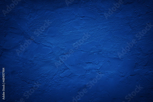 Black dark blue painted concrete wall. Toned grunge background. Rough grainy plaster texture surface. Bright deep color. Cobalt shade. Exterior. Close-up. Design. Empty space.