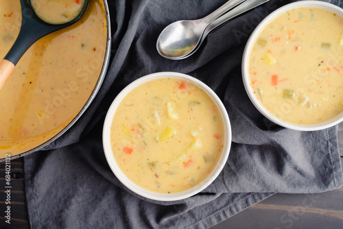 Bowls of German Potato Soup (Kartoffelsuppe) Next to a Dutch Oven: Bowls of vegetable soup with spoons next to a cast-iron Dutch oven and ladle photo
