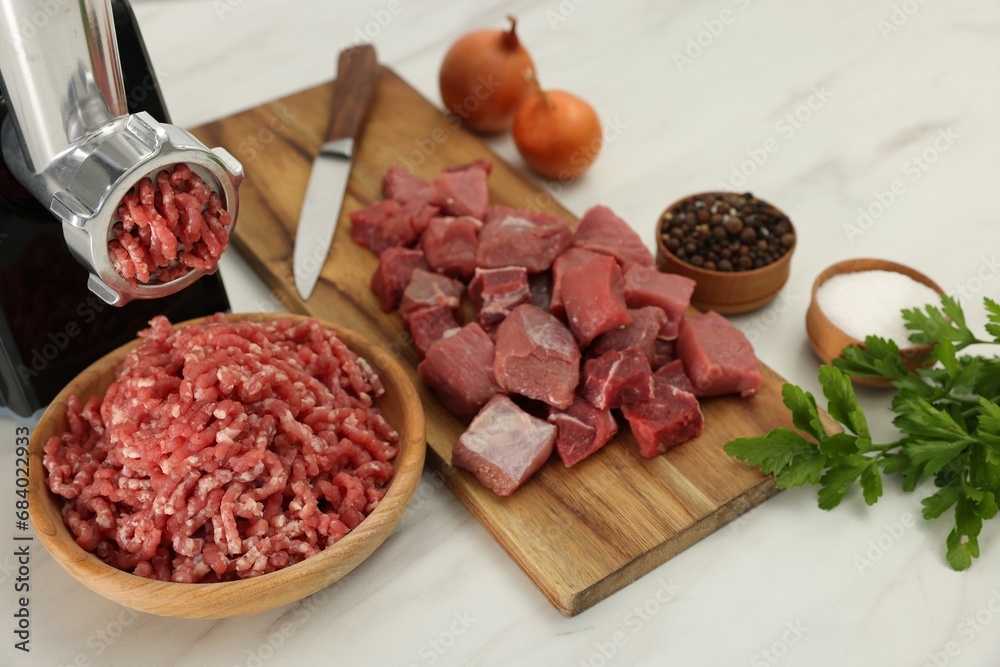 Electric meat grinder with beef and products on white marble table, above view Electric meat grinder with beef and products on white marble table, above view