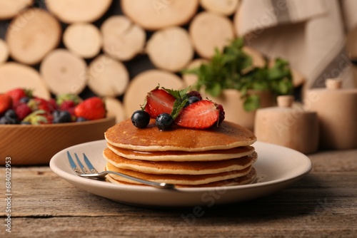 Tasty pancakes with fresh berries and mint on wooden table