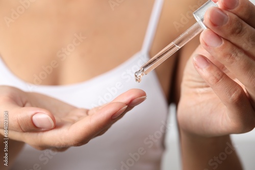 Woman applying cosmetic serum onto her finger  closeup