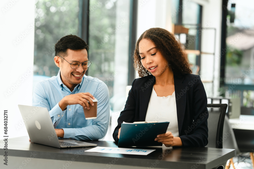 Asian business man and African American woman engaging in business discussion, possibly about merger or joint venture. two companies become one, one of companies often survives while other disappears Asian business man and African American woman engaging in business discussion, possibly about merger or joint venture. two companies become one, one of companies often survives while other disappears