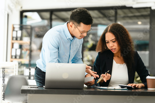 Asian business man and African American woman engaging in business discussion, possibly about merger or joint venture. two companies become one, one of companies often survives while other disappears