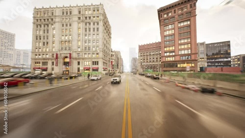 The camera quickly glides down a narrow downtown street between cars and dense buildings.