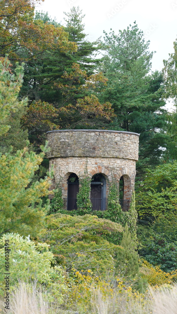The old bell tower view with the autumn woods as background in the old garden
