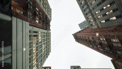 The camera moves backwards down a narrow busy street, looking perpendicularly upward.