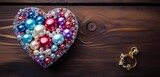 A top-down view of a charming heart-themed gift box placed on a polished wooden surface, with scattered decorative beads.