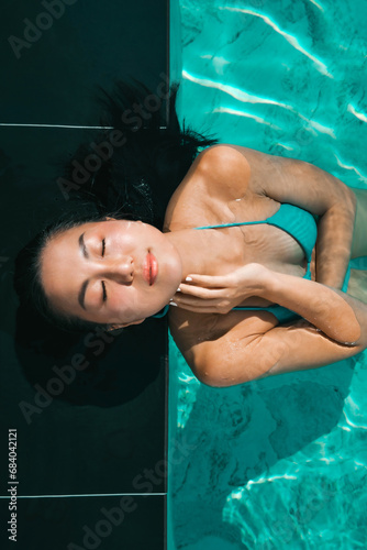 Young asian woman relaxing in the water, Beautiful girl relaxing at overwater infinity pool luxury resort. Spa, wellness, swimming.