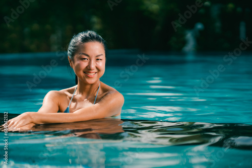 Young asian woman relaxing in the water  Beautiful girl relaxing at overwater infinity pool luxury resort. Spa  wellness  swimming.