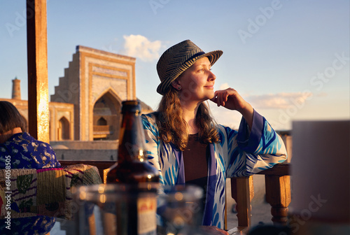 Tourist woman in ethnic dress near Madrassah in Ichan Kala of Khiva photo