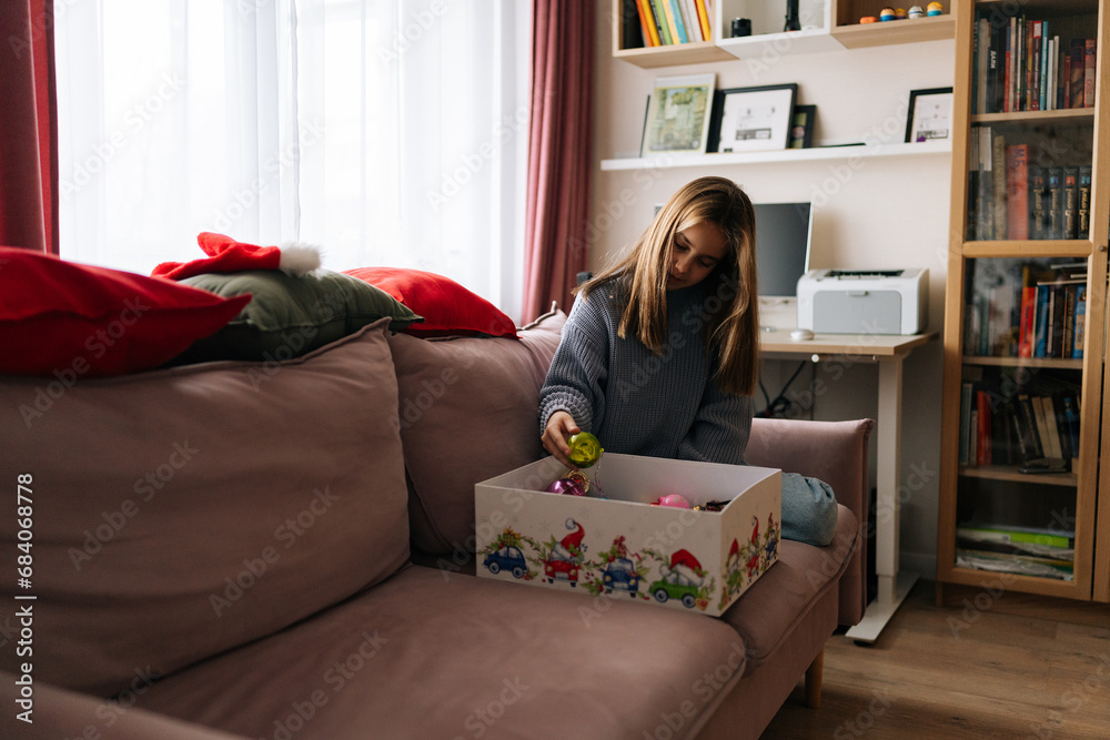Φωτογραφία Portrait of happy cute little girl preparing for holidays, choosing festive Christmas tree ball in box with toys