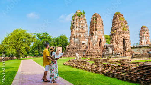 Ayutthaya, Thailand at Wat Mahathat, a couple of men and women with a hat and tourist map visiting Ayutthaya Thailand. Tourists with a map looking at a old temple in Thailand photo