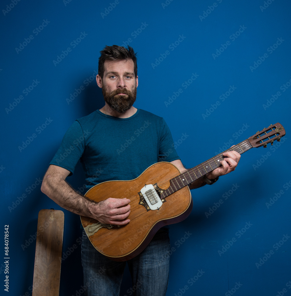 Obraz premium Young man playing guitar with blue background