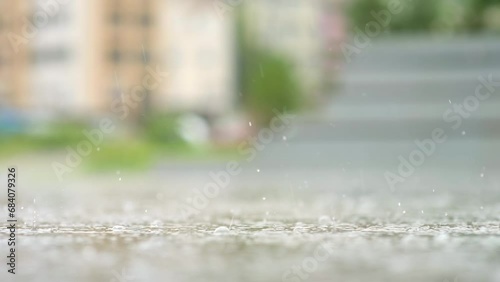 Atmospheric video of rainstorm in a city. Heavy rain and splashes puddles taken from low point. Large drops break on the pavement. Slow motion