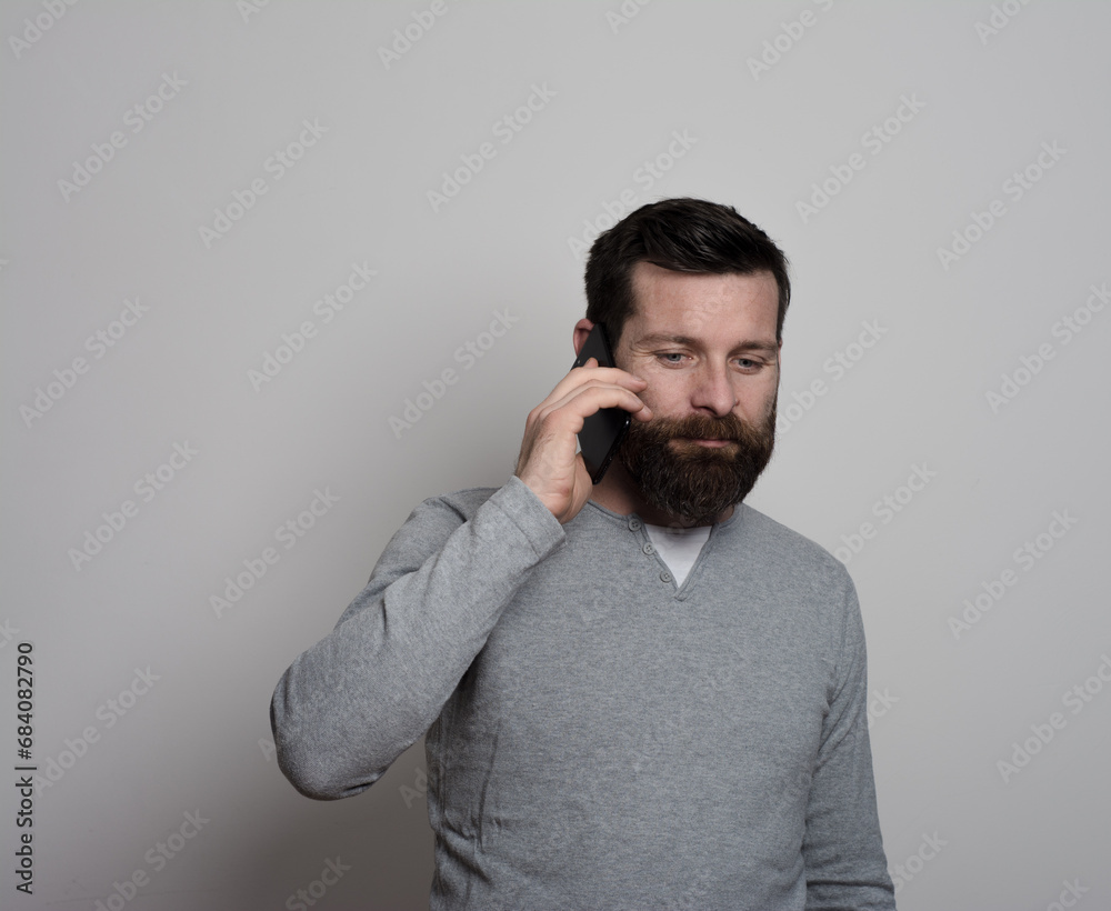 Attractive man chatting or typing text message using cell phone isolated over white background