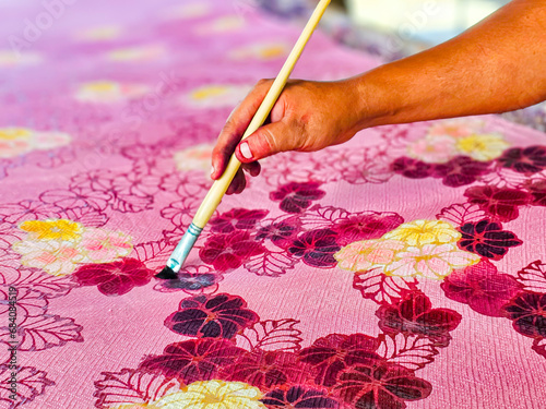 Making batik by drawing beautiful patterns by hand.