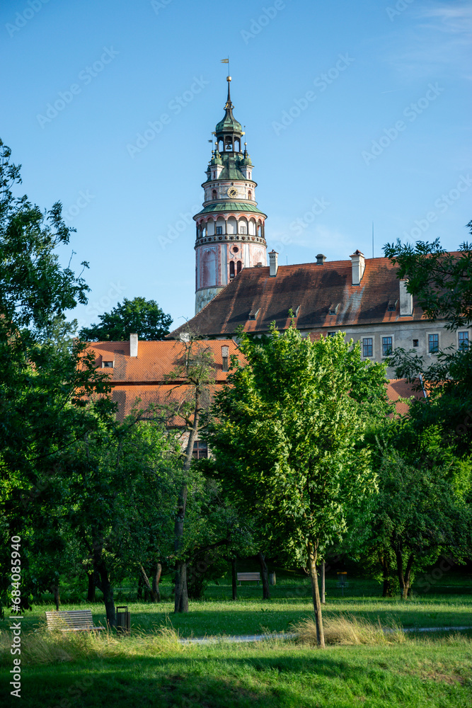 Park with grass, trees and a tall castle tower in Cesky Krumlov, Czech Republic.