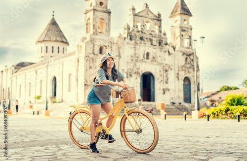 Lifestyle of a happy girl in hat on bicycle on the street. Granada, Nicaragua. Happy girl in hat riding a bicycle at sunset. Tourism and travel concept