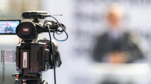 TV camera records a speaker on stage, delivering impactful insights and engaging the audience, on fair