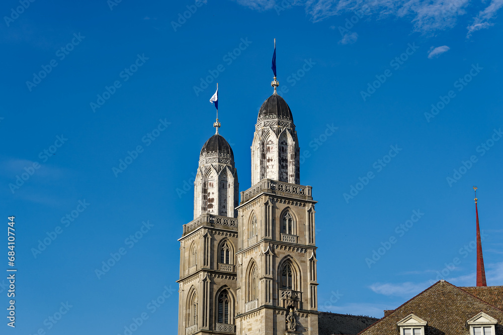 Twin towers with flags of City of Zürich and Canton Zürich on top of church towers of protestant church Great Minster on a sunny summer evening. Photo taken July 7th, 2023, Zurich, Switzerland.