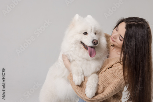 girl playing and hugging a white Samoyed dog on a clean white background, caring for a dog, large white dog