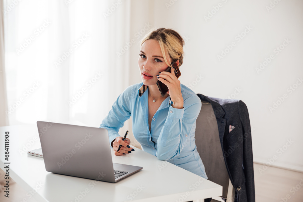 Woman talking on smartphone working on computer online Woman talking on smartphone working on computer online