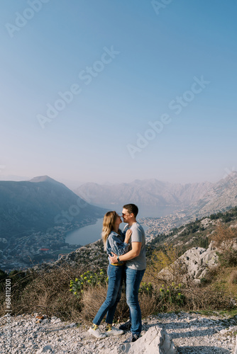 Man and woman embrace and almost kiss on a mountain overlooking the Bay of Kotor. Montenegro