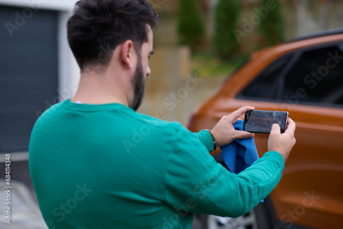 man taking photos on a smartphone of a car preparing for sale 
