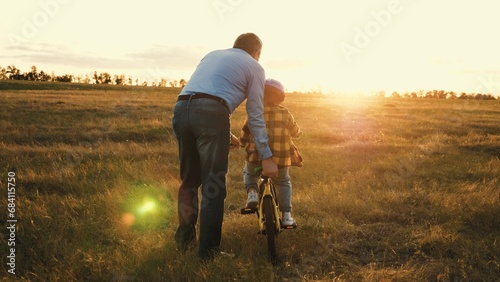 Supportive father gives gentle push to help persistent son steer bicycle