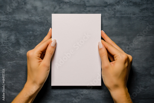 Blank Greeting Card Mockup With Hands Holding The Invitation Card Vertically. Dark Gray Background. Empty Greeting Card Template