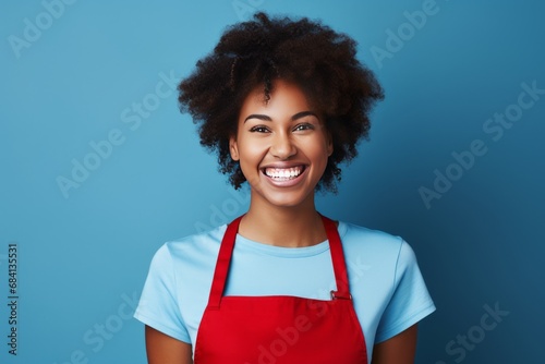 Cheerful Woman in Red Apron Against Vibrant Blue Background