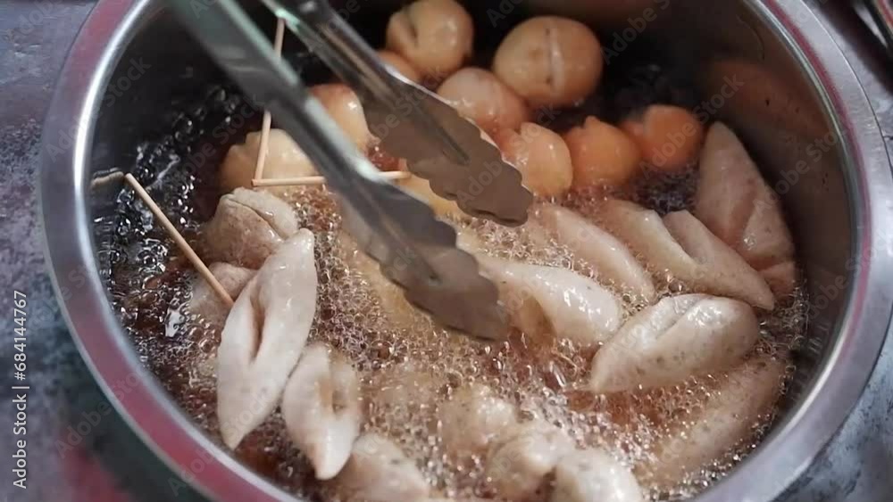 Asian merchant hands is deep fried meatballs in a pot of boiling oil on street food in market of Thailand Asian merchant hands is deep fried meatballs in a pot of boiling oil on street food in market of Thailand