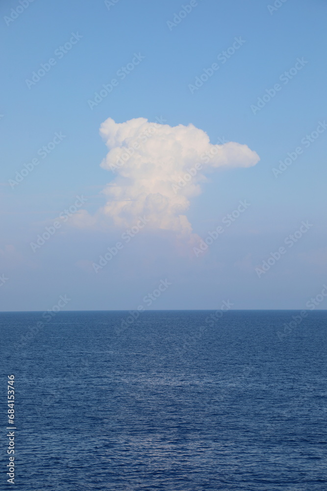 simple vertical background with blue sea below and a tall white cloud in the sky