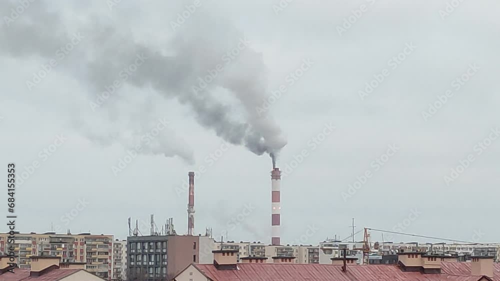 Pipes of a heating station smoke against the backdrop of a city landscape in winter Pipes of a heating station smoke against the backdrop of a city landscape in winter